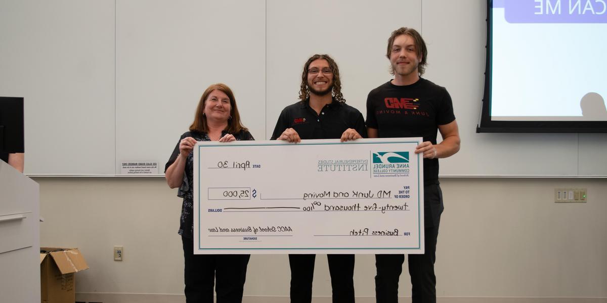 Two Business Pitch winners holding an oversized check with Stephanie Goldenberg.